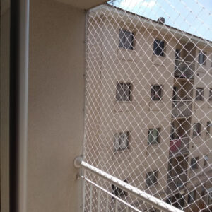 ede de proteção branca instalada em sacada de apartamento em Curitiba, garantindo a segurança de crianças no ambiente.