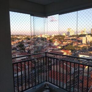 Vista da cidade de Curitiba a partir de uma sacada totalmente telada com rede de proteção, garantindo a segurança de animais de estimação.